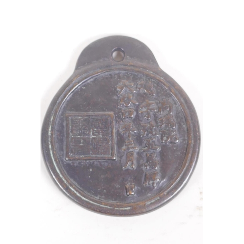 56 - A Chinese bronze pendant decorated with running horses, the reverse with calligraphy, 10cm diameter