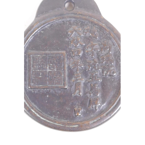 56 - A Chinese bronze pendant decorated with running horses, the reverse with calligraphy, 10cm diameter