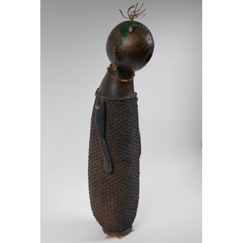 58 - An African basket work and hollowed gourd doll with painted details, possibly Congolese, 59cm high