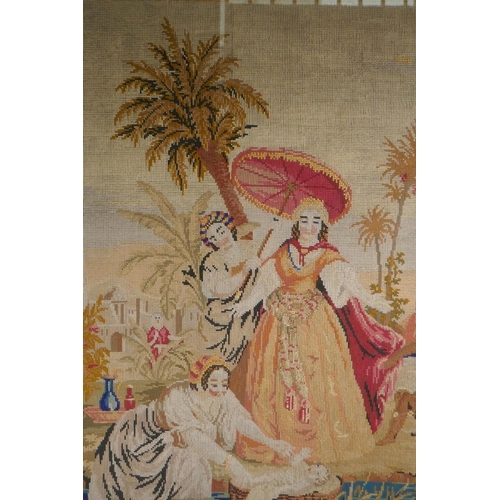 84 - A C19th needlework tapestry panel depicting Moses and the Pharoah's daughter at the river's edge, in... 