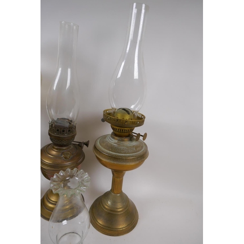 101 - A near pair of brass column oil lamps and another similar, with one engraved shade and various chimn... 