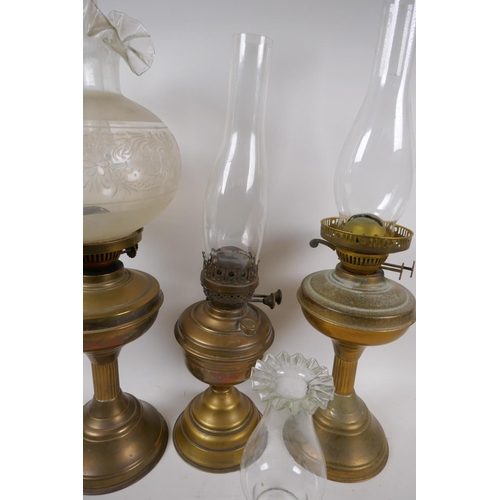 101 - A near pair of brass column oil lamps and another similar, with one engraved shade and various chimn... 