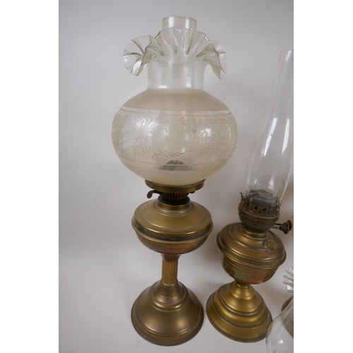 101 - A near pair of brass column oil lamps and another similar, with one engraved shade and various chimn... 