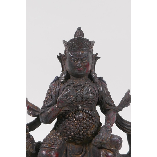 126 - A Sino Tibetan bronze of an armoured deity seated on a kylin, with the remnants of gilt and lacquere... 