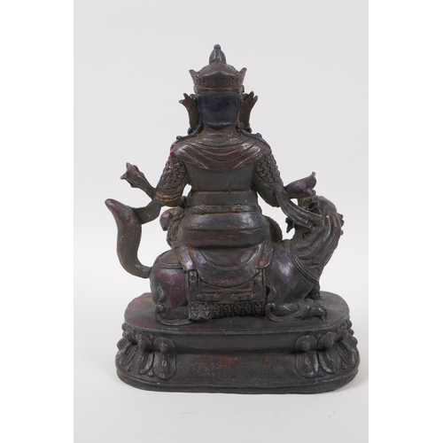 126 - A Sino Tibetan bronze of an armoured deity seated on a kylin, with the remnants of gilt and lacquere... 