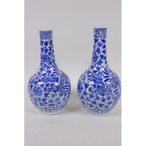 56 - A pair of Chinese blue and white bottle vases decorated with dragons amongst foliage, KangXi 4 chara... 