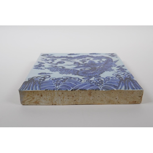 58 - A Chinese blue and white porcelain temple tile decorated with a dragon in flight, 20cm x 20cm