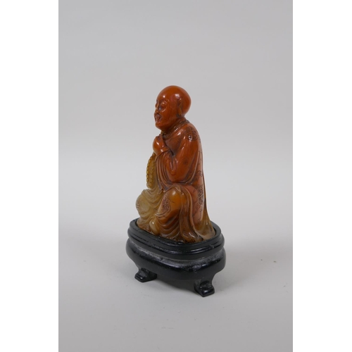 75 - A Chinese soapstone style composition figure of Lohan with a seal to base, with display stand and bo... 