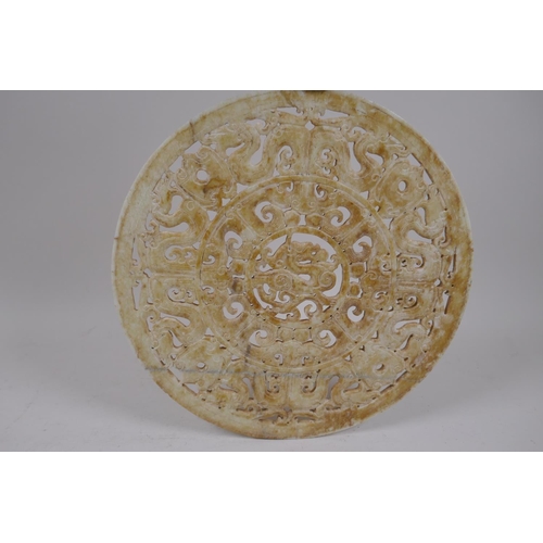 56 - A late C19th/early C20th Chinese carved and pierced celadon hardstone pi-disc with archaic dragon de... 