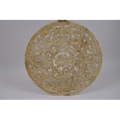 56 - A late C19th/early C20th Chinese carved and pierced celadon hardstone pi-disc with archaic dragon de... 