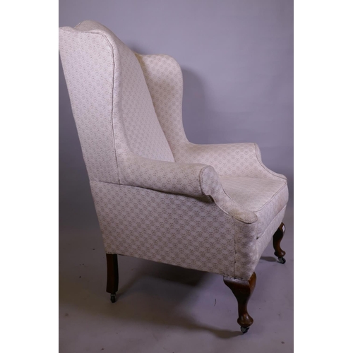 1142 - A Georgian style wing armchair with high back, raised on cabriole supports