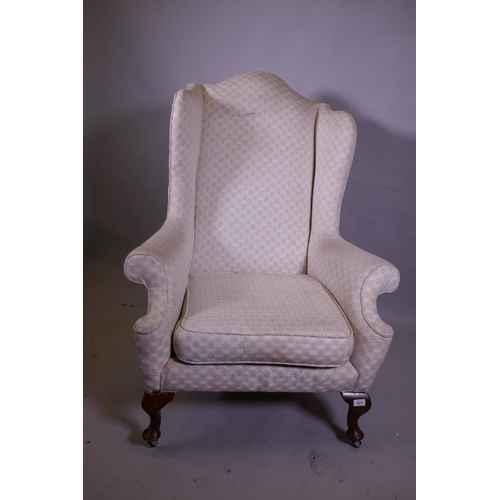 1142 - A Georgian style wing armchair with high back, raised on cabriole supports