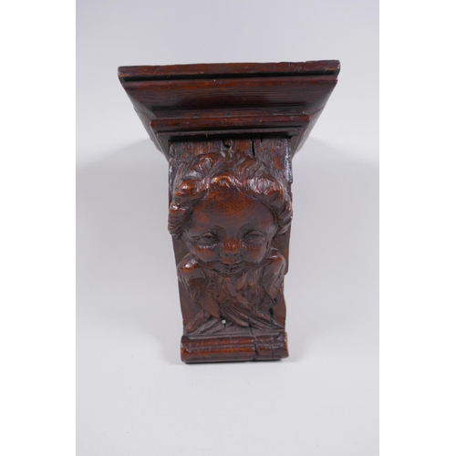 5 - A C17th adapted carved oak bracket/term, with cherub mask decoration, 23cm