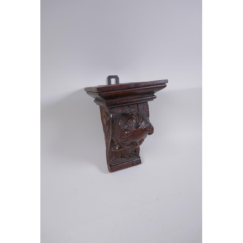 5 - A C17th adapted carved oak bracket/term, with cherub mask decoration, 23cm