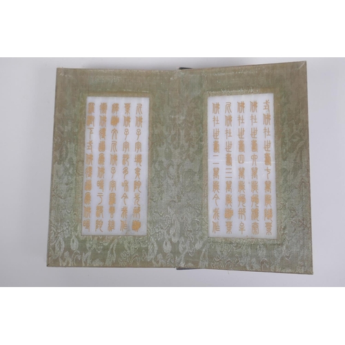 51 - A Chinese wood and fabric bound book containing white jade tablets with chased and gilt character in... 