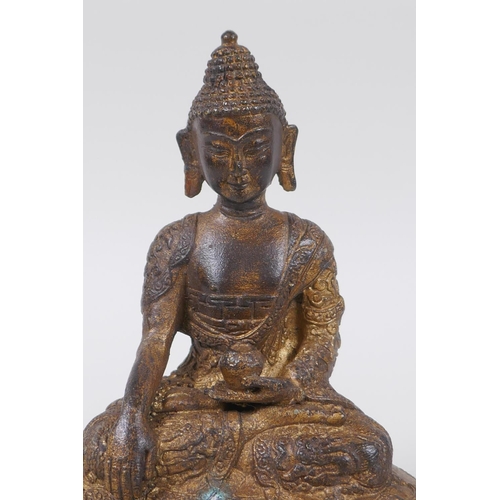 73 - A Tibetan bronze of Buddha seated on a lotus throne, with the remnants of gilt patina, 15cm high