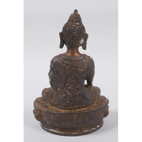 73 - A Tibetan bronze of Buddha seated on a lotus throne, with the remnants of gilt patina, 15cm high