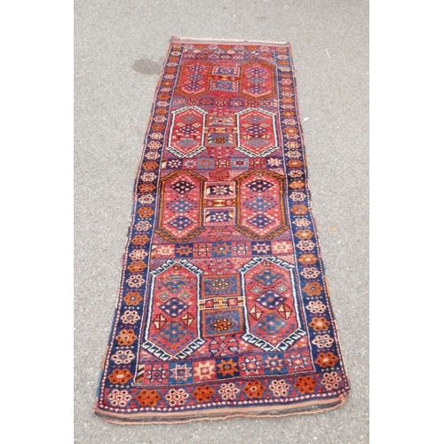 1152 - A Kurdish red ground full pile village rug/runner with unique geometric design, 290cm x 98cm