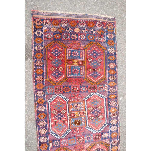 1152 - A Kurdish red ground full pile village rug/runner with unique geometric design, 290cm x 98cm