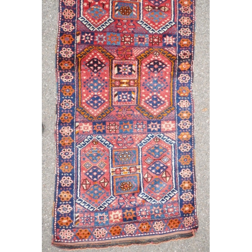 1152 - A Kurdish red ground full pile village rug/runner with unique geometric design, 290cm x 98cm