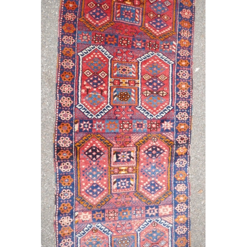 1152 - A Kurdish red ground full pile village rug/runner with unique geometric design, 290cm x 98cm