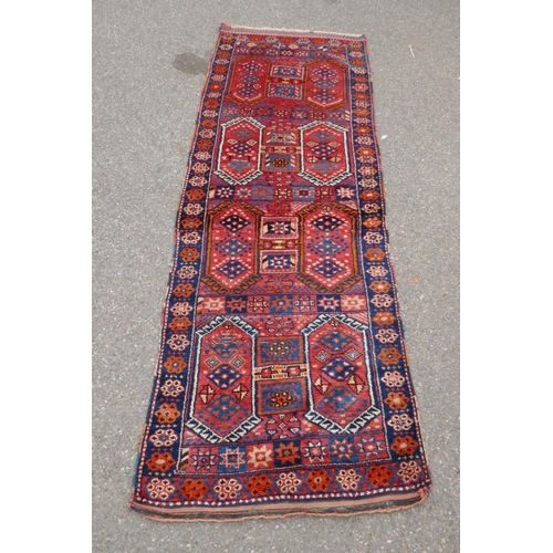 1152 - A Kurdish red ground full pile village rug/runner with unique geometric design, 290cm x 98cm