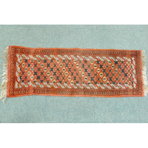 1109 - A small hand woven wool village runner with trellis design on a red ground, 140 x 50cm