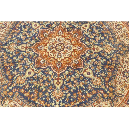 1126 - A wool carpet with Persian style designs on a red field with blue borders, 180cm diameter