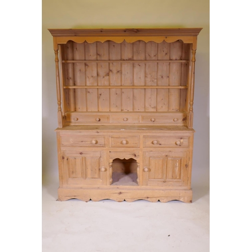 1111 - A pine dresser with an open delft rack, the base with two cupboards flanking a dog kennel, 158 x 43c... 