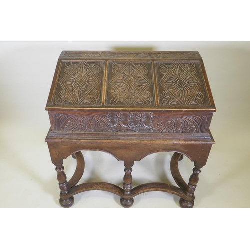 1023 - A carved oak bible box on stand, with triple panel fall front, the stand raised on baluster turned s... 