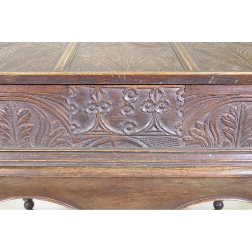 1023 - A carved oak bible box on stand, with triple panel fall front, the stand raised on baluster turned s... 