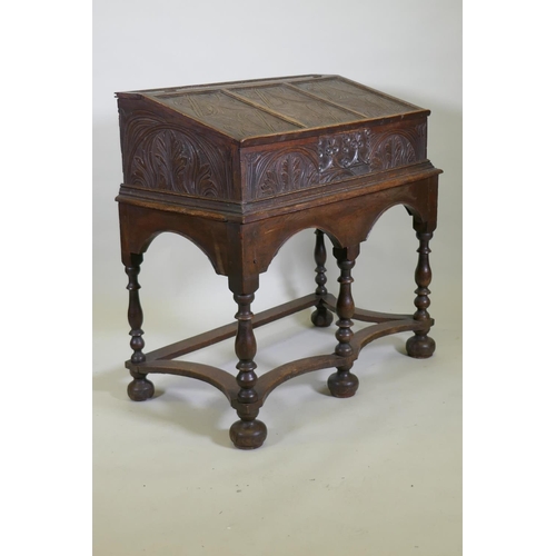 1023 - A carved oak bible box on stand, with triple panel fall front, the stand raised on baluster turned s... 