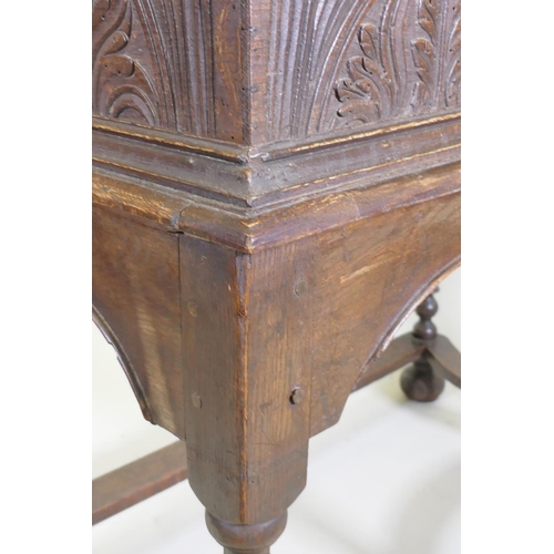 1023 - A carved oak bible box on stand, with triple panel fall front, the stand raised on baluster turned s... 