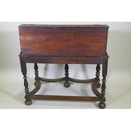 1023 - A carved oak bible box on stand, with triple panel fall front, the stand raised on baluster turned s... 