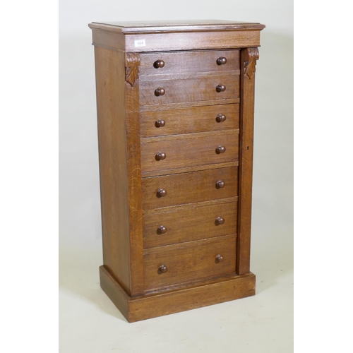 1024 - An oak Wellington chest of seven graduated drawers with  carved corbels and locking bark, raise... 