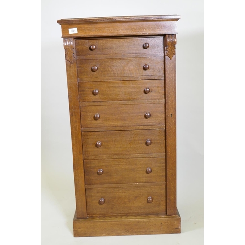 1024 - An oak Wellington chest of seven graduated drawers with  carved corbels and locking bark, raise... 