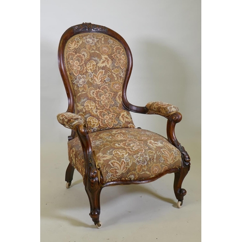 1029 - A Victorian walnut spoon back show frame arm chair, with carved decoration and scroll arms, raised o... 