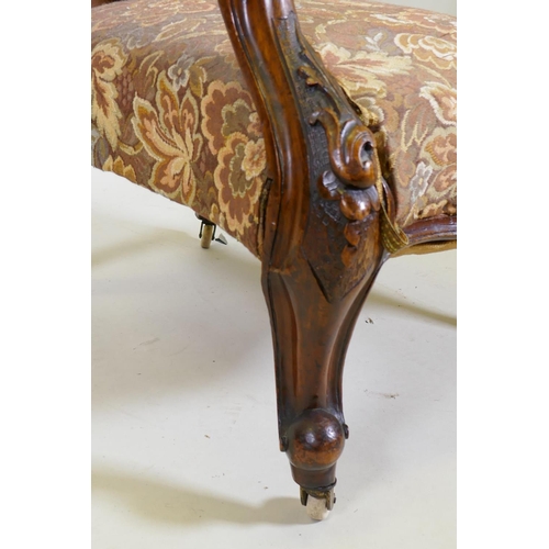 1029 - A Victorian walnut spoon back show frame arm chair, with carved decoration and scroll arms, raised o... 