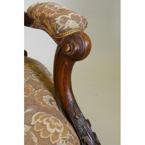 1029 - A Victorian walnut spoon back show frame arm chair, with carved decoration and scroll arms, raised o... 