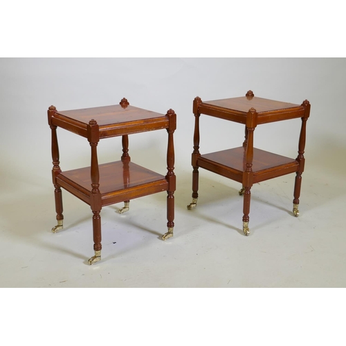 1038 - A pair of small yew wood two tier lamp tables, raised on turned columns with brass castors, 32 x 32 ... 