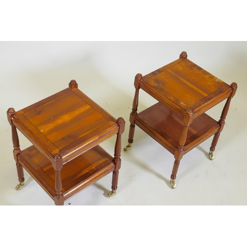 1038 - A pair of small yew wood two tier lamp tables, raised on turned columns with brass castors, 32 x 32 ... 