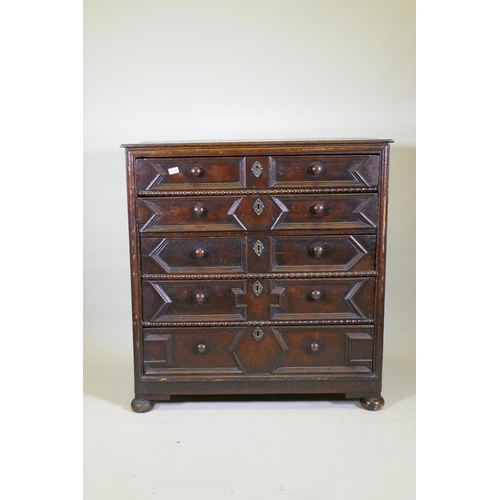 1039 - A Jacobean oak chest of five drawers, with moulded and bobbin turned decoration, raised on bun suppo... 