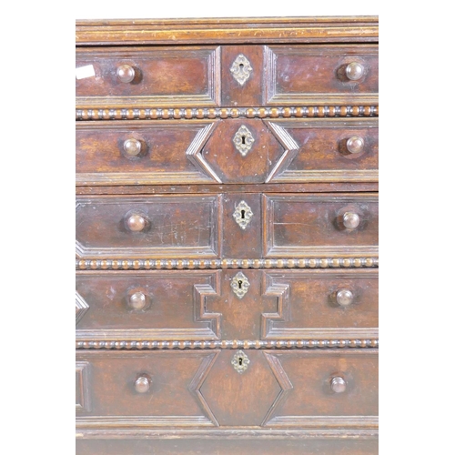 1039 - A Jacobean oak chest of five drawers, with moulded and bobbin turned decoration, raised on bun suppo... 