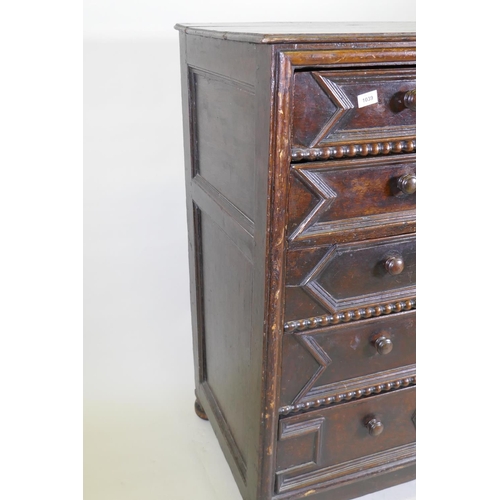 1039 - A Jacobean oak chest of five drawers, with moulded and bobbin turned decoration, raised on bun suppo... 