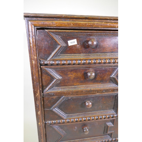 1039 - A Jacobean oak chest of five drawers, with moulded and bobbin turned decoration, raised on bun suppo... 