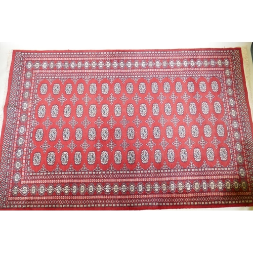 1054 - An antique red ground wool Bokhara rug, 240 x 156cm