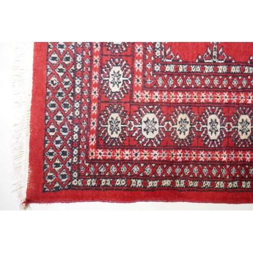 1054 - An antique red ground wool Bokhara rug, 240 x 156cm