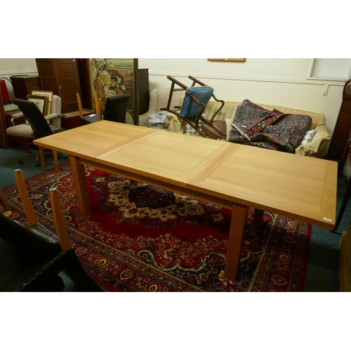 1055 - A contemporary golden oak dining table, with pull out ends, central fold out leaf, raised on removab... 