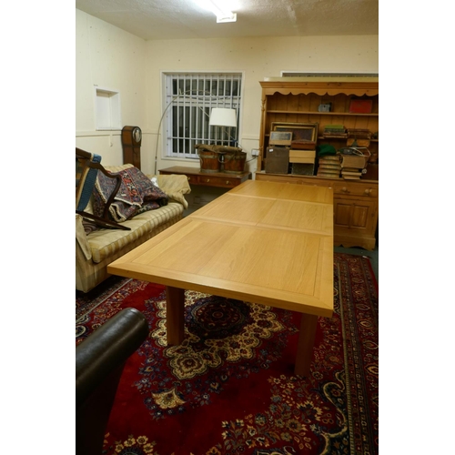 1055 - A contemporary golden oak dining table, with pull out ends, central fold out leaf, raised on removab... 