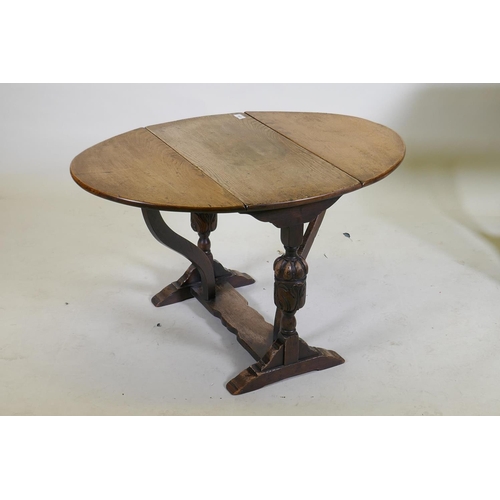 1056 - An oak drop leaf occasional table, raised on carved end supports united by a shaped stretcher, 68 x ... 